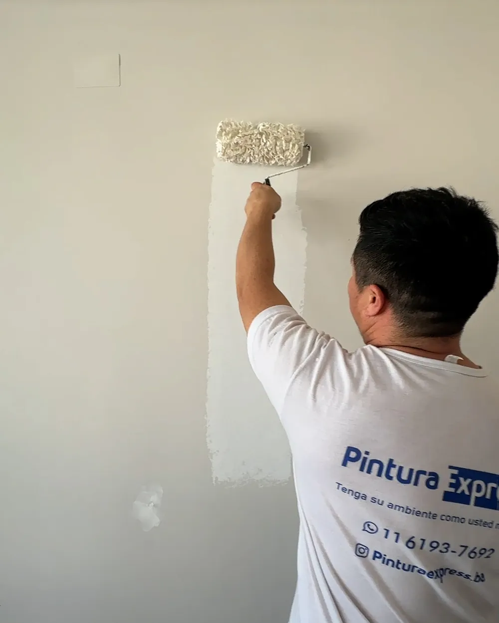 Pintor de Pintura Express con remera de la empresa aplicando enduido en una pared