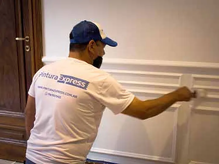Pintor de Pintura Express aplicando esmalte sobre la carpintería de madera de la Embajada de Costa Rica