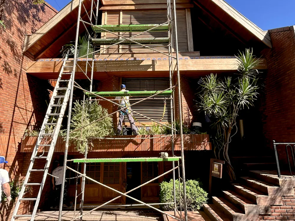 Casa en Villa Pueyrredón con andamios montados para pintar la fachada de madera y ladrillo